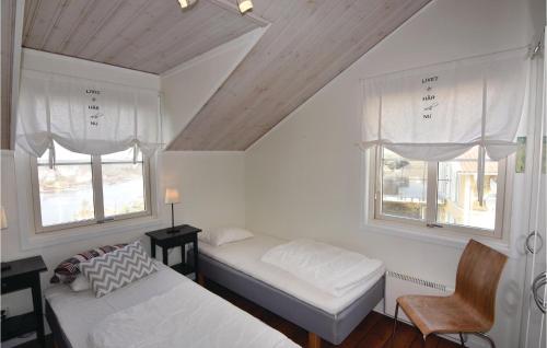 a bedroom with two beds and a chair and two windows at Beautiful Home In Kyrkesund With Sauna in Kyrkesund