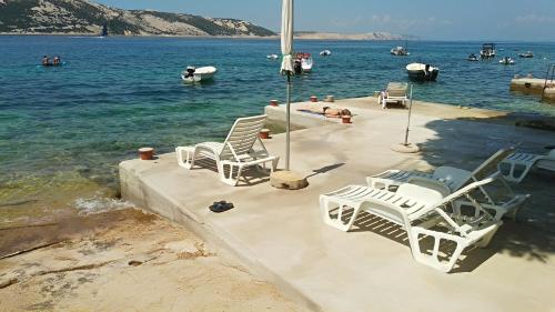 un groupe de chaises assises sur un quai dans l'eau dans l'établissement Beach House Apartments Stara Novalja, à Stara Novalja