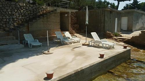a group of chairs sitting on a concrete patio at Sea breeze Apartments with boat Anchorage in Stara Novalja