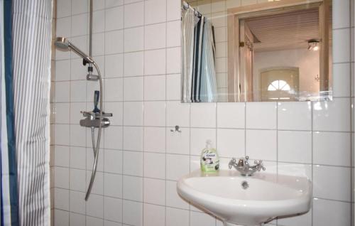 GärsnäsにあるNice Home In Grsns With 2 Bedroomsの白いタイル張りのバスルーム(シンク、鏡付)