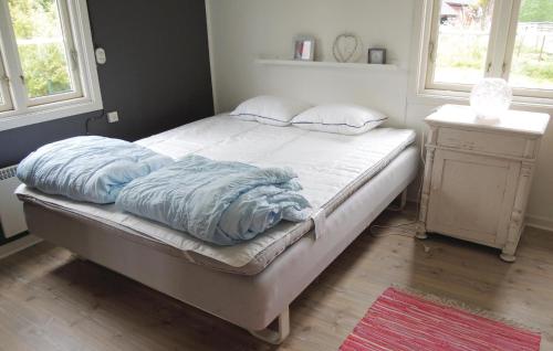 een bed met blauwe lakens in een kamer met ramen bij Awesome Home In lmhult With Kitchen in Apelhult