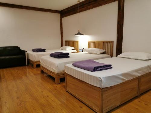a room with three beds and a couch at Beijing Downtown Travelotel in Beijing