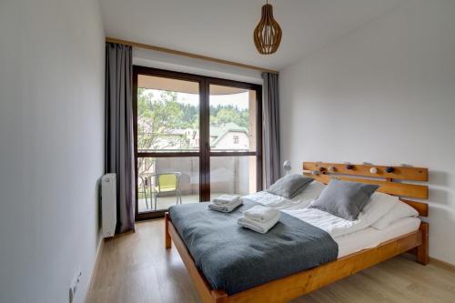 a bedroom with a bed and a large window at Krynica Apartamenty Rodzinny Apartament w Centrum 43 in Krynica Zdrój