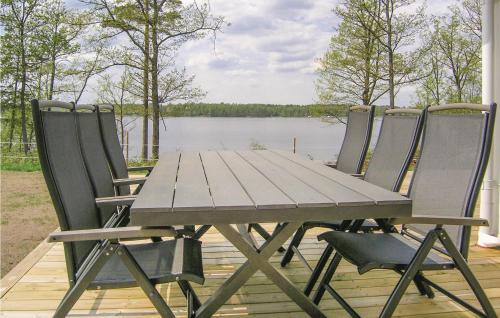 a wooden table and four chairs on a deck with a lake at Beautiful Home In Bolmsö With Wifi in Bolmsö