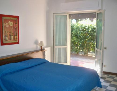 a bedroom with a blue bed and a sliding glass door at Airone RTA in Orbetello