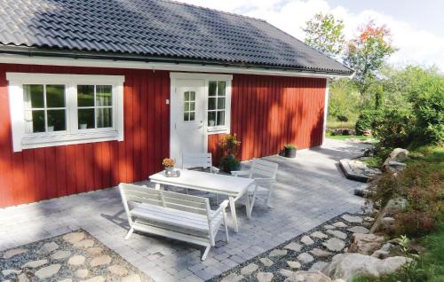 a red house with a table and benches in front of it at Holiday Home Sandåkra Vetlanda in Vetlanda