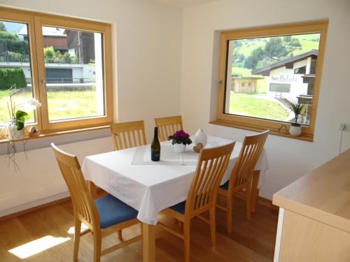 uma sala de jantar com uma mesa e cadeiras e duas janelas em Wiesen Appartment em Schwarzenberg im Bregenzerwald