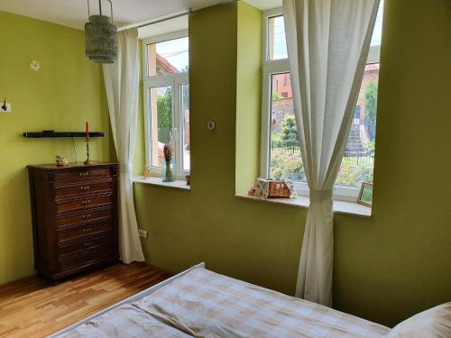 1 dormitorio con paredes y ventanas verdes y 1 cama en Virág Wellness Villa, en Pécs