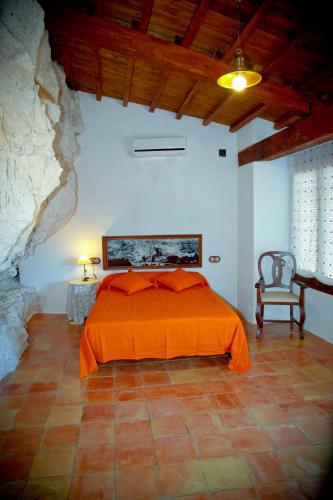 a bedroom with an orange bed and a chair at Casa Rural La Bodeguilla in Alcalá del Júcar