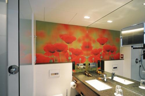 a bathroom with a painting of red flowers on the wall at LAGO hotel & restaurant am see in Ulm