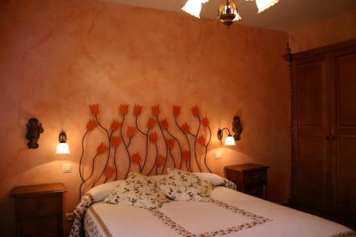 a bedroom with a bed and two lights on the wall at Casa de la Yaya in Hoyos del Espino