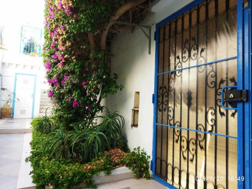 une porte bleue avec des fleurs sur le côté du bâtiment dans l'établissement Villa Azaiiza, à Sousse