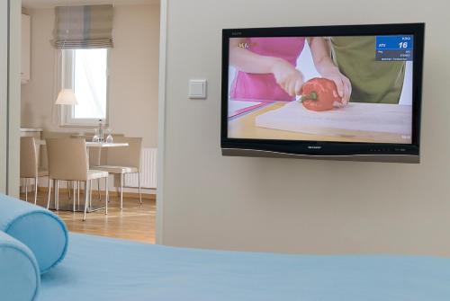 a television hanging on a wall in a living room at Nymphe Strandhotel & Apartments in Binz