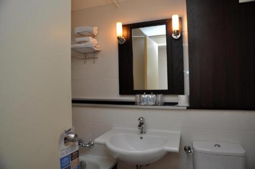 a bathroom with a sink and a toilet and a mirror at Hôtel Inn Design Resto Novo Carquefou in Carquefou