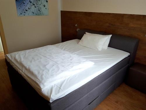 a bed with white sheets and a wooden headboard at Hotel PrimaVera parco in Fürth