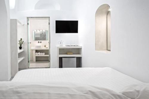 a white bedroom with a bed and a mirror at Hotel Thireas in Fira