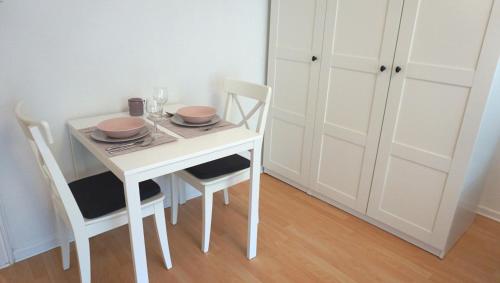 a white dining room table with two bowls and plates on it at City Apartment Bahnhofnah in Kiel
