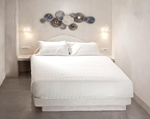 a bedroom with a large white bed with a chandelier at Hotel Thireas in Fira