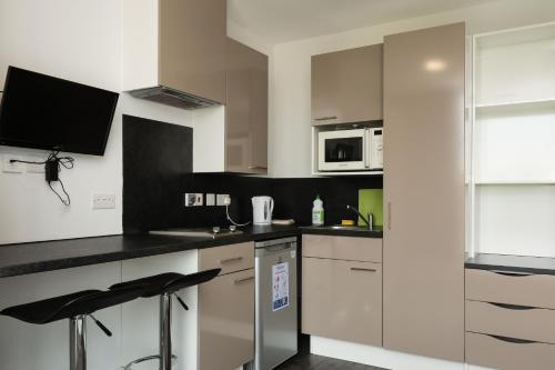 a kitchen with white cabinets and black counter tops at Destiny Student - Holyrood (Brae House) in Edinburgh
