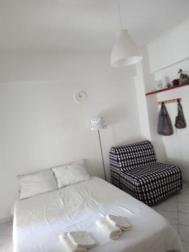 a white bedroom with a bed and a chair at Vanessa's studio in Agia Triada