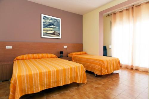 two beds in a hotel room with orange sheets at Nou Rocamar in Sant Carles de la Ràpita