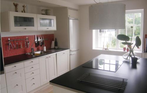 a kitchen with white cabinets and a black counter top at Nice Home In Beddingestrand With Sauna in Beddinge Strand