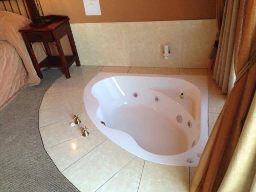 y baño con bañera y suelo de baldosa. en Blue Haze Country Lodge, en Estcourt