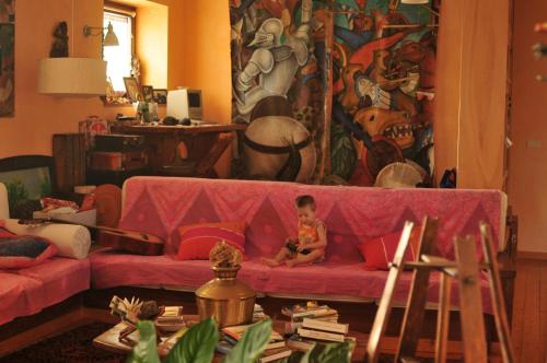 a child sitting on a pink couch in a living room at Azienda Agricola Il Querceto in Marsico Vetere