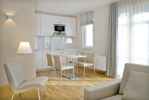a kitchen and living room with a table and chairs at Nymphe Strandhotel & Apartments in Binz
