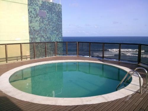 a swimming pool on the balcony of a building with the ocean at Pier Sul Apartaments in Salvador
