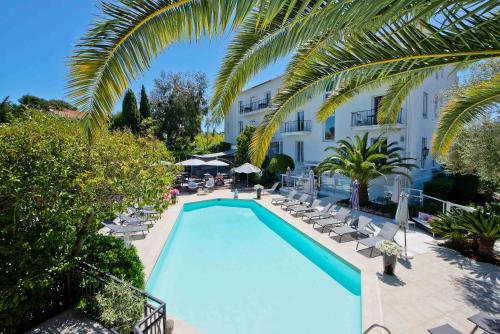 widok na basen z krzesłami i hotel w obiekcie Hôtel La Villa Cap d’Antibes w mieście Juan-les-Pins