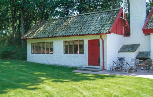 a small white building with a red door on a yard at Three-Bedroom Holiday Home In Tomelilla in Tomelilla