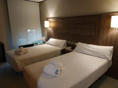 two beds in a hotel room with towels on them at Balneario de Ledesma in Vega de Tirados