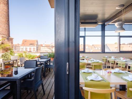 a restaurant with tables and chairs and windows at Ghent River Hotel in Ghent