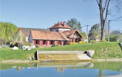 a house sitting next to a pond in front of a house at Lovely Home In Frise With Wifi in Frise