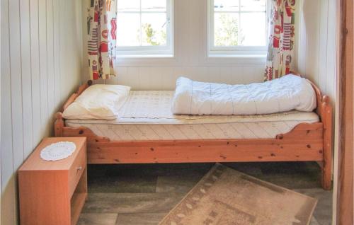 a wooden bed in a room with two windows at Beautiful Home In Jondal With Kitchen in Jondal