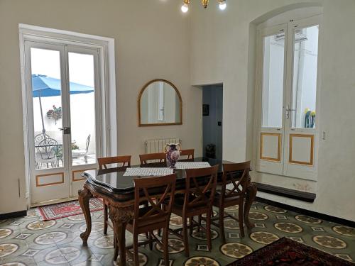 a dining room with a table and chairs and windows at B&B Palazzo Antonelli in Monopoli