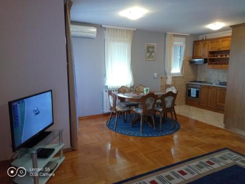 uma sala de estar com uma mesa e cadeiras e uma televisão em Apartmani Almica em Zagreb