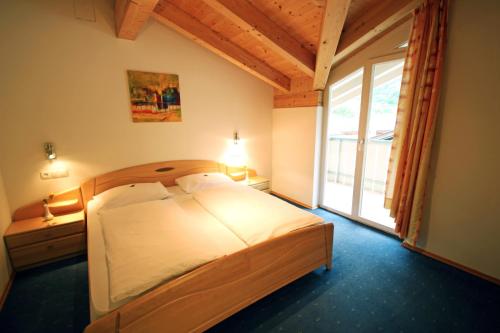 a bedroom with a bed and a large window at Garni Sonnblick in Naturno