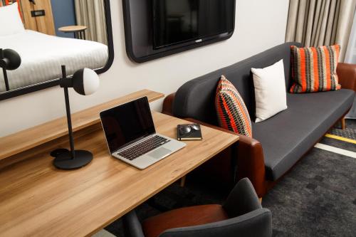 a room with a desk with a laptop and a couch at ibis Styles London Gloucester Road in London