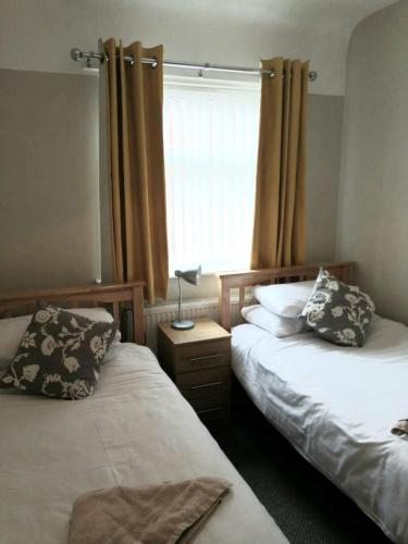 a bedroom with two beds and a window with curtains at Liverpool City House in Liverpool