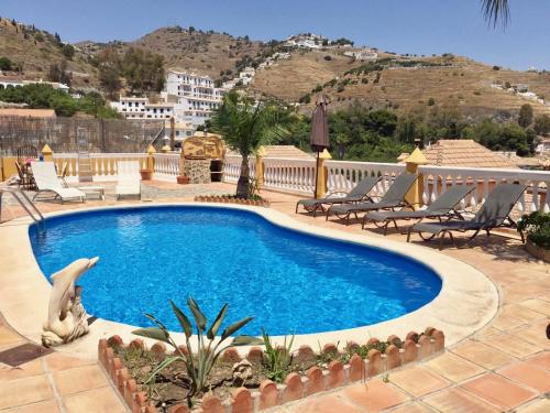 una piscina en un complejo con sillas y montañas en CHALET CON PISCINAS Y VISTAS DE ENSUEÑO, en Almuñécar