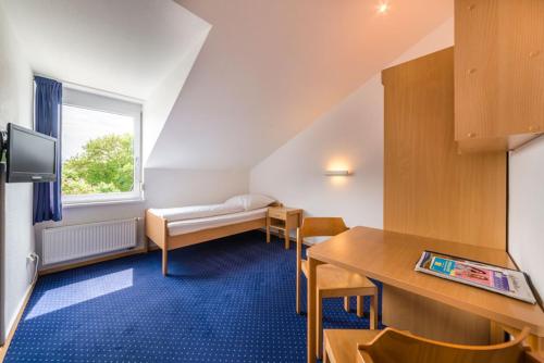 Pokój z łóżkiem, stołem i krzesłami w obiekcie CAP Rotach w mieście Friedrichshafen
