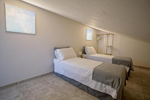 two beds in a room with white walls at CASA VACANZE MARCONI 22 in Marone