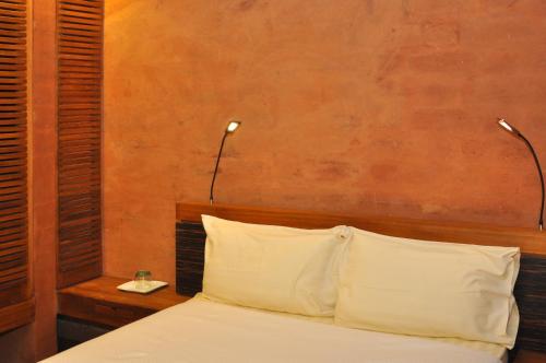 a bedroom with a bed with two lights on the wall at Hotel Le Djoloff in Dakar