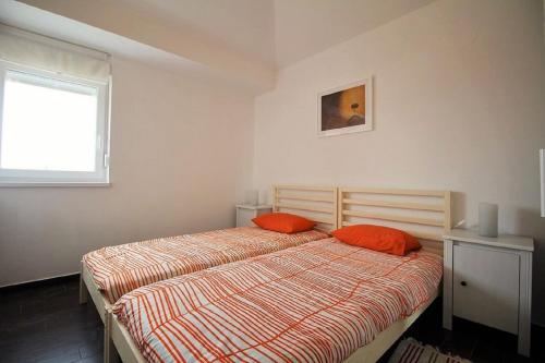 a bedroom with a bed with orange pillows and a window at Apartment Electro with Jacuzzi in Novalja
