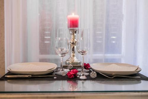 a table with a candle and two plates and glasses at Au domaine des anges, 3 gîtes luxueux avec Jacuzzi privatif, sauna, mini-piscine, piscine extérieure chauffée en saison in Bain-de-Bretagne