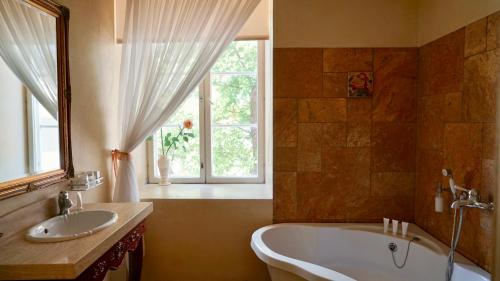 a bathroom with a tub and a sink and a window at Grand Rose SPA Hotel in Kuressaare
