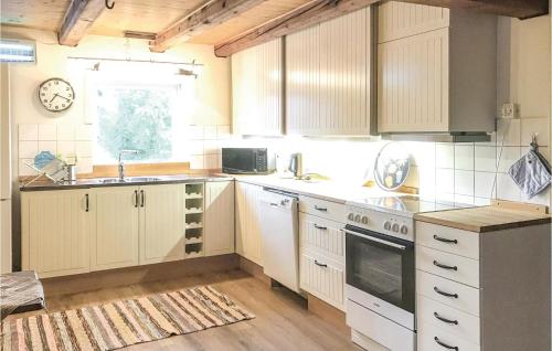 a kitchen with white cabinets and a clock on the wall at 2 Bedroom Beautiful Home In Rimforsa in Skälhamra