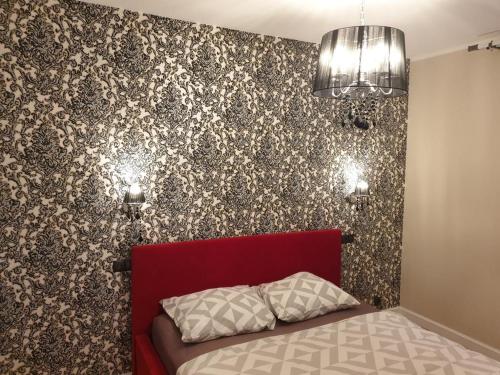 a bedroom with a red bed and a wall at Apartamenty Promenada in Warsaw